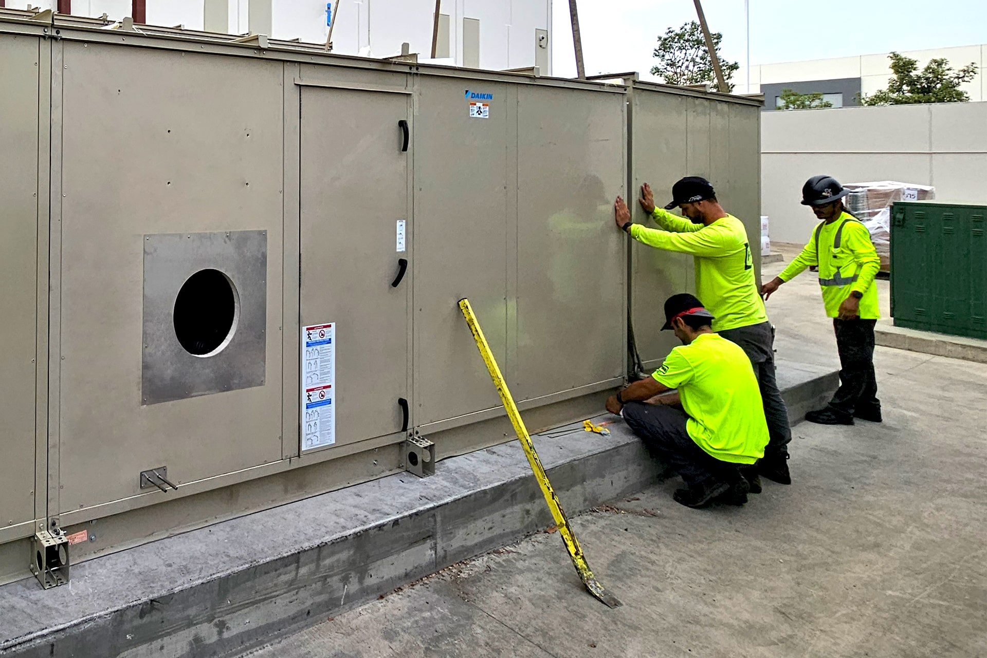 Three FOSS General Contractor employees working on outdoor heaters and ducts.