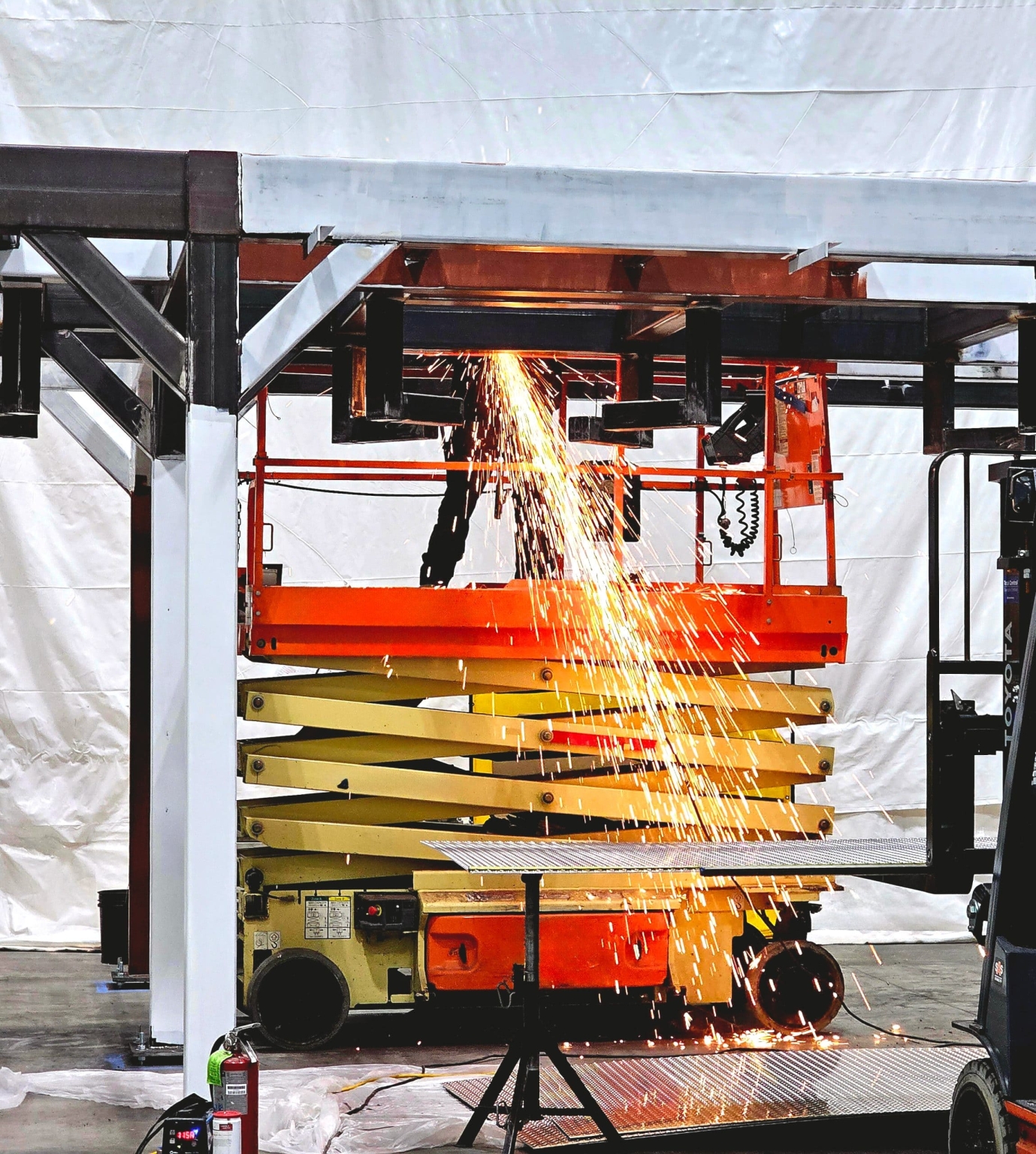 grinding down welds on structural steel platform while on scissor lift